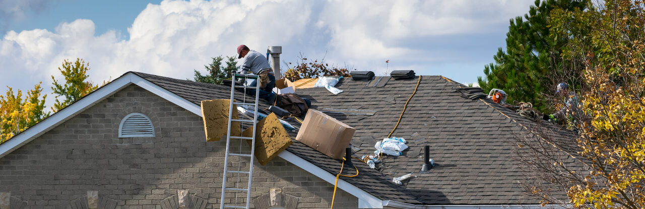 A roofing crew working from a ladder on a single storey home