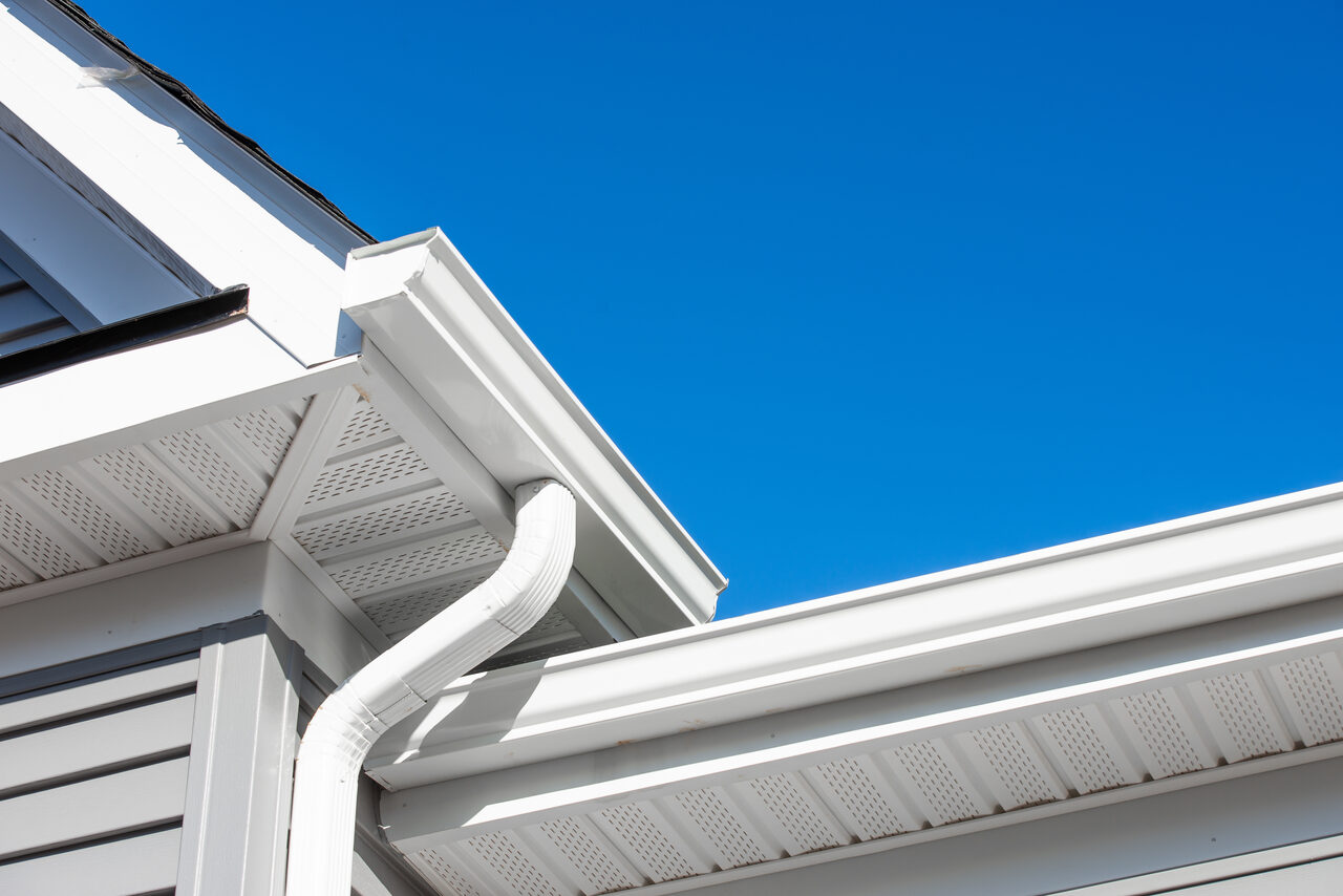 A white downspout at the corner of a house
