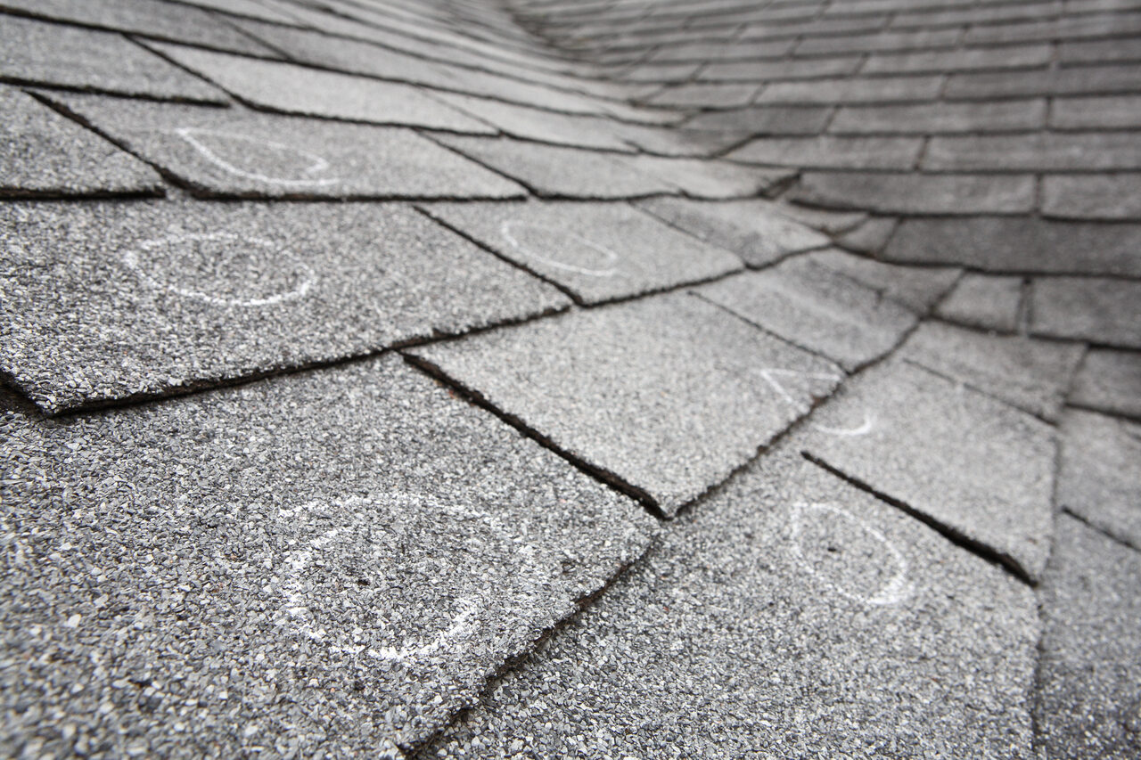 Hail impact marks circled in chalk during a roof inspection