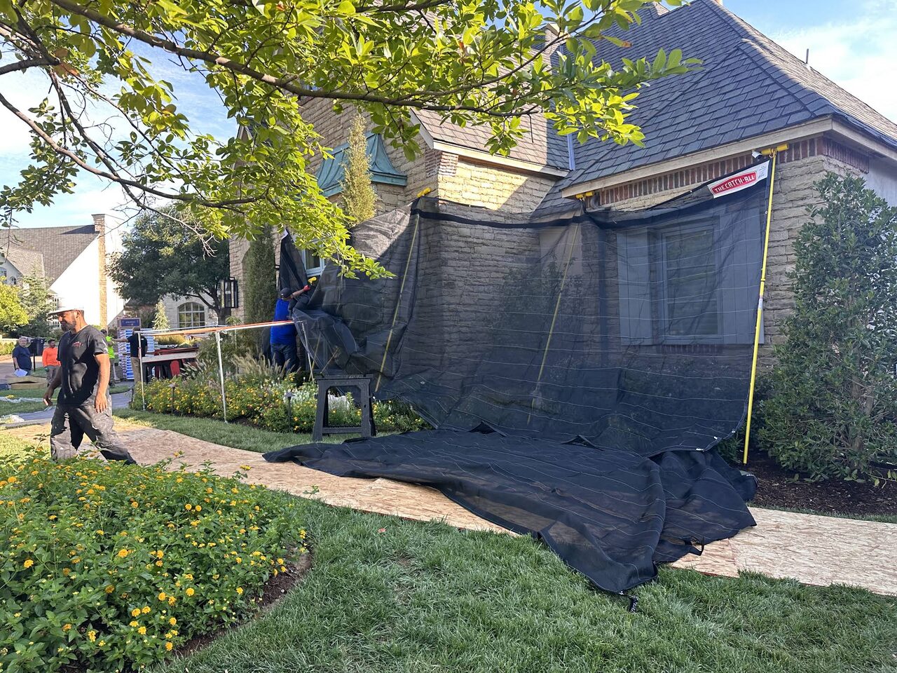 Protective netting and covers laid over landscaping and planting beds during roofing work