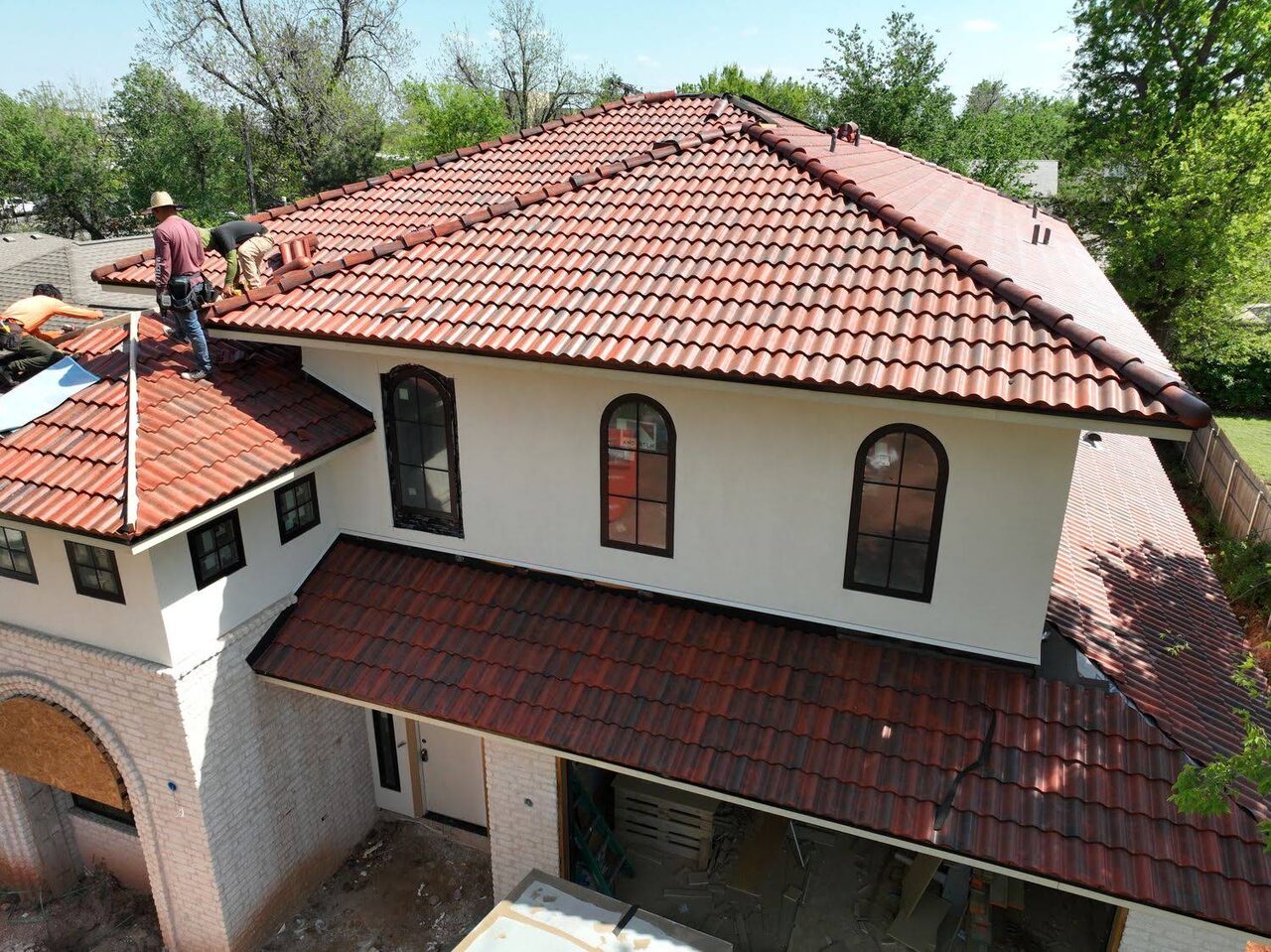 Champion Roofing crew setting clay tile on the ridge of a stucco home in Oklahoma City