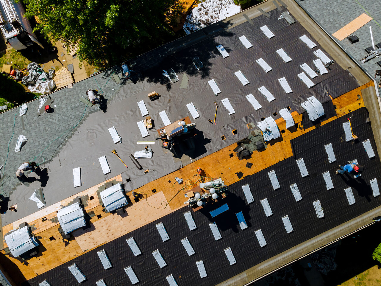 Aerial view of a roof replacement in progress with shingle bundles staged on the deck
