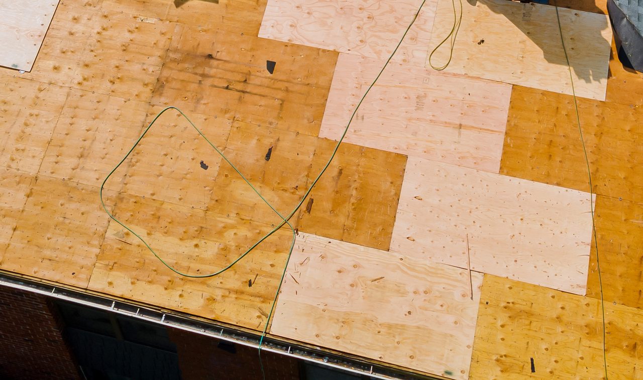 New decking sheets set in among the old sheathing on a roof opened up for replacement