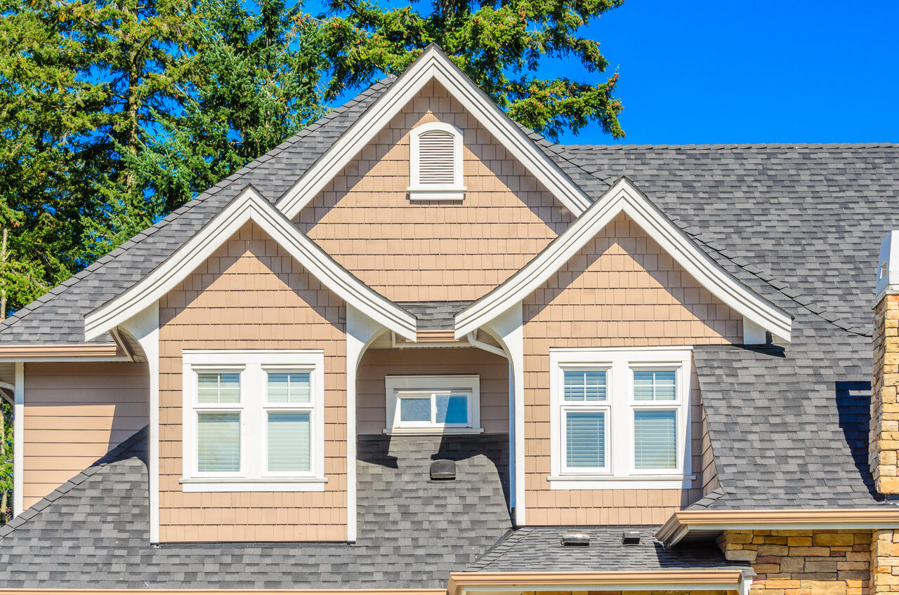 A tan brick home with a newly installed shingle roof