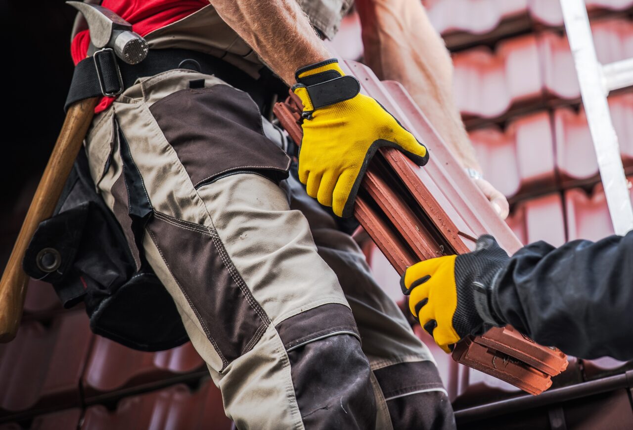 Gloved hands setting a clay tile into place