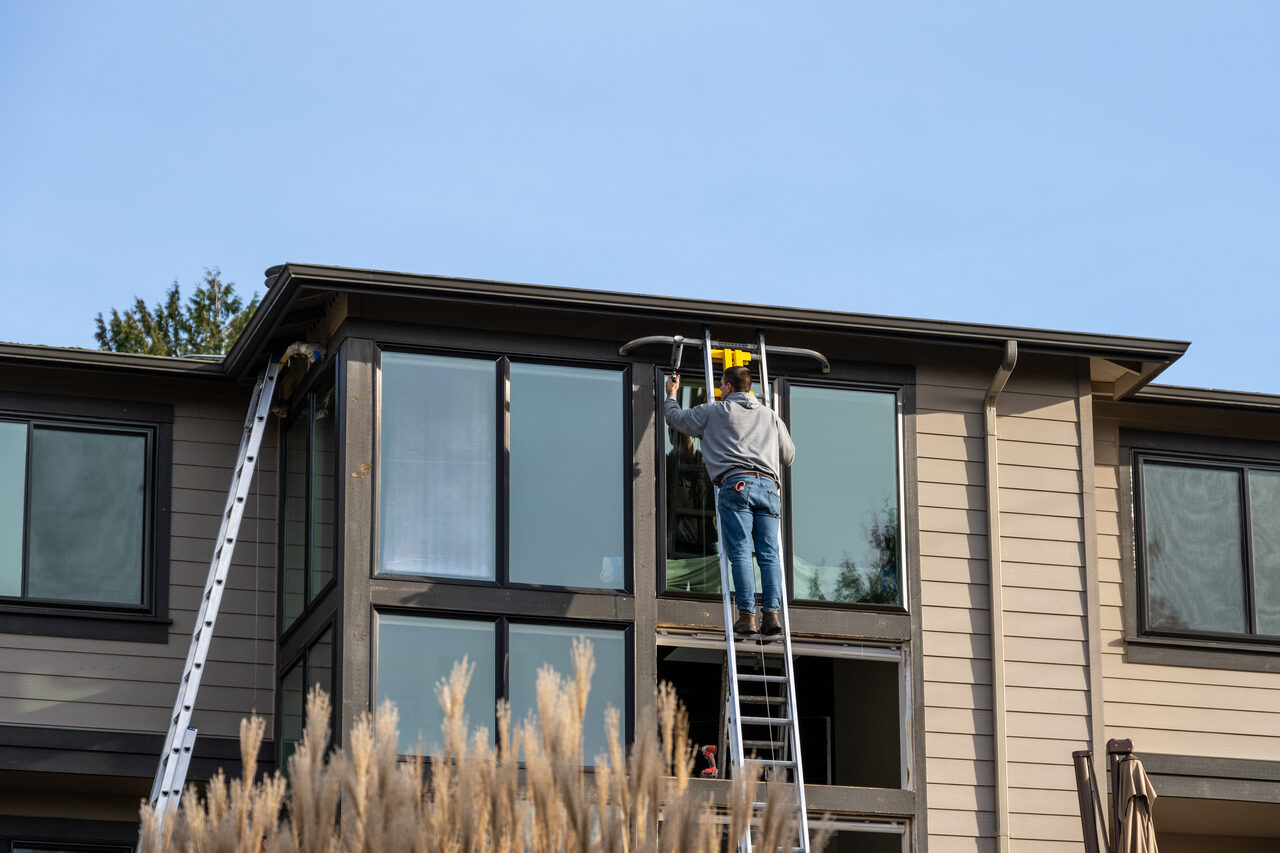 An installer working from a ladder at a second storey window